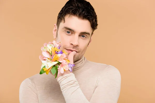 Homem com flores alstroemeria na mão tocando lábios isolados em bege — Fotografia de Stock