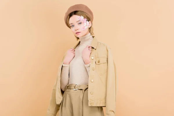 Woman with flowers on face wearing beret and standing isolated on beige — Stock Photo