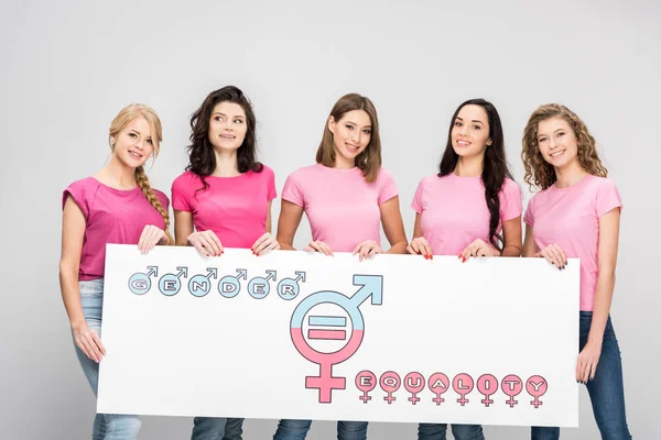 Hermosas mujeres jóvenes sosteniendo un gran cartel con el símbolo de igualdad de género aislado en gris - foto de stock
