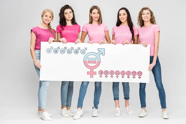 Mujeres jóvenes atractivas sosteniendo un gran cartel con el símbolo de igualdad de género sobre fondo gris - foto de stock