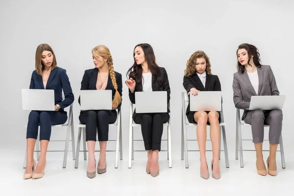 Молода жінка дивиться на ноутбук колеги-жінки ізольовані на сірому — стокове фото