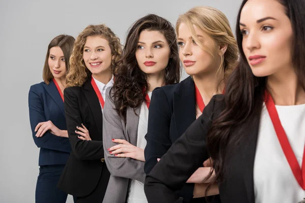 Enfoque selectivo de hermosas mujeres de negocios jóvenes de pie con medallas aisladas en gris - foto de stock