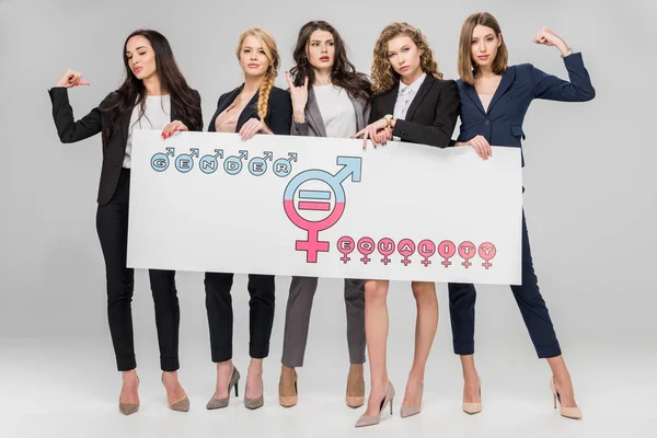 Jóvenes empresarias con gran cartel con símbolo de igualdad de género sobre fondo gris - foto de stock
