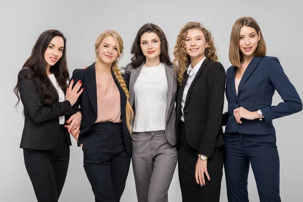 Schöne junge Geschäftsfrauen, die isoliert auf grau stehen und lächeln — Stockfoto