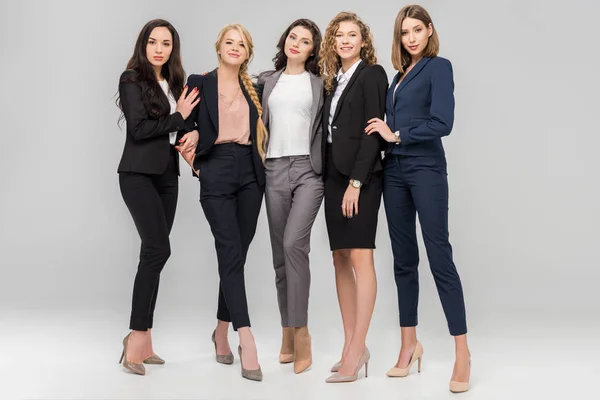 Schöne junge Geschäftsfrauen stehen und lächeln auf grauem Hintergrund — Stockfoto