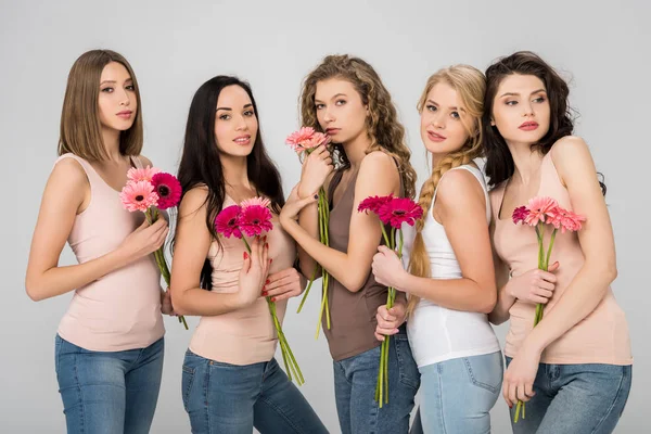 Hermosas chicas sosteniendo flores de color rosa y de pie aislado en gris - foto de stock