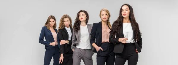 Belles jeunes femmes debout avec les mains dans des poches isolées sur gris — Photo de stock