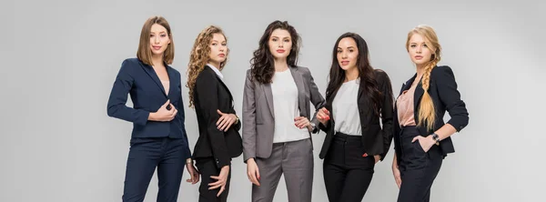 Beautiful successful women standing with hands in pockets isolated on grey — Stock Photo