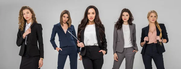 Confident successful young women standing with hands in pockets isolated on grey — Stock Photo