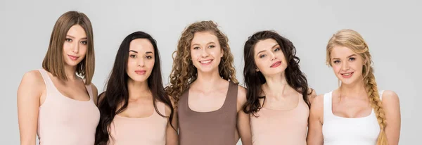 Happy girls embracing while standing together isolated on grey — Stock Photo