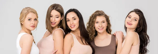 Happy female friends hugging while standing together isolated on grey — Stock Photo