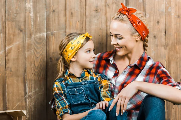 Niño feliz sonriendo mientras mira a la madre cerca de valla de madera - foto de stock