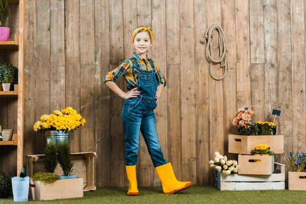 Cheerful kid posing in yellow shoes near flowers and plants — Stock Photo