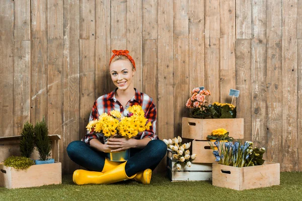 Belle femme assise avec les jambes croisées et tenant des fleurs — Photo de stock