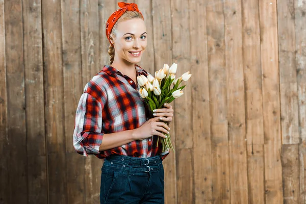 Весела жінка посміхається, тримаючи тюльпани в руках — стокове фото