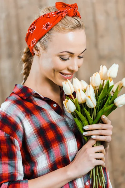 Весела жінка посміхається, пахнучи тюльпанами — стокове фото