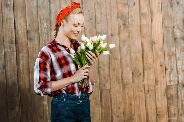 Весела жінка посміхається, дивлячись на тюльпани — Stock Photo