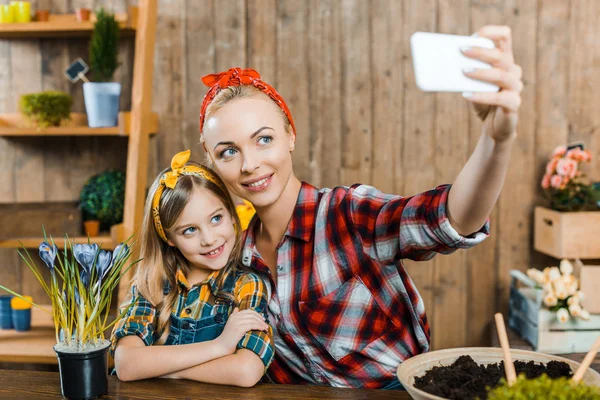 Selective focus of beautiful mother taking selfie with cute daughter — Stock Photo