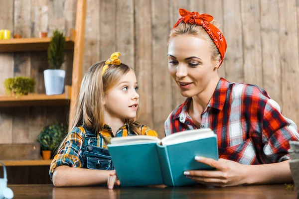 Belle mère lecture livre à fille mignonne — Photo de stock