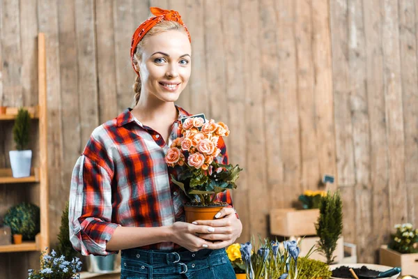 Cheerful woman standing and holding pot with flowers — Stock Photo