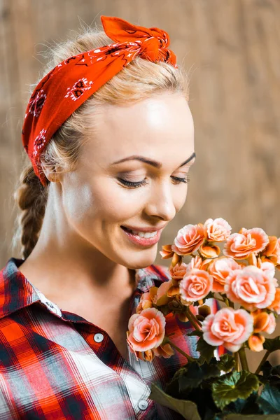 Cheerful woman standing with closed eyes and smelling flowers — Stock Photo