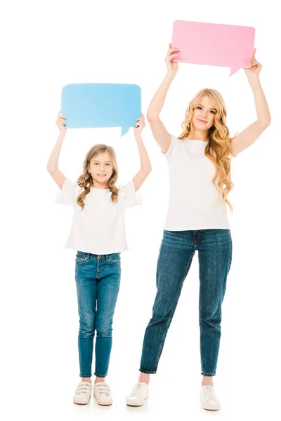 Hermosa mujer con adorable hija sosteniendo el habla burbujas en las manos levantadas aisladas en blanco - foto de stock