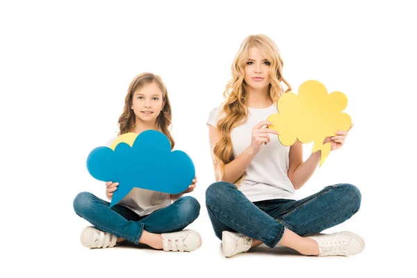 Pretty mother and cute daughter sitting on floor with crossed legs and holding thought bubbles while looking at camera on white background — Stock Photo