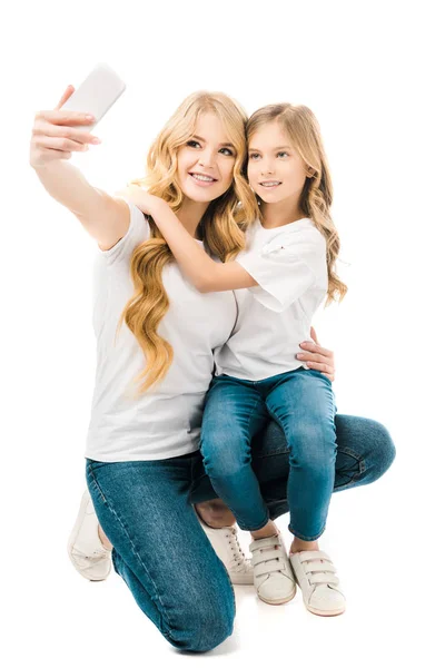 Mãe feliz tomando selfie enquanto abraçando filha isolada no branco — Fotografia de Stock