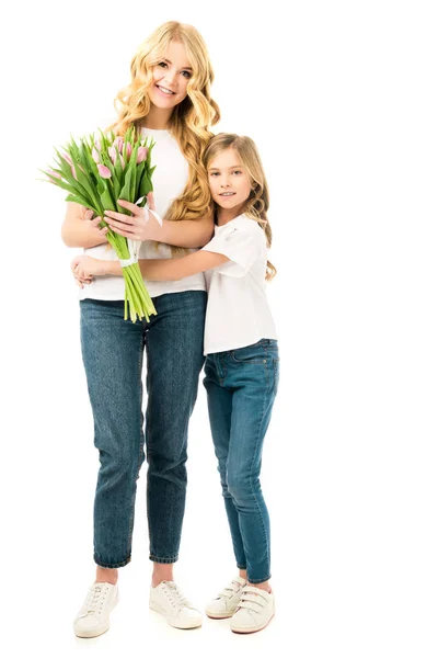 Мила дочка обіймає маму, тримає букет красивих тюльпанів ізольовані на білому — стокове фото