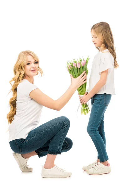 Cute daughter gifting beautiful bouquet of tulips to mother isolated on white — Stock Photo