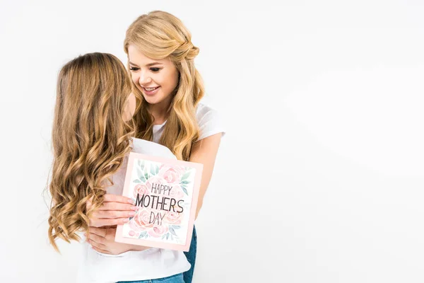 Feliz hermosa mujer con feliz madre día tarjeta de felicitación abrazando adorable hija sobre fondo blanco - foto de stock