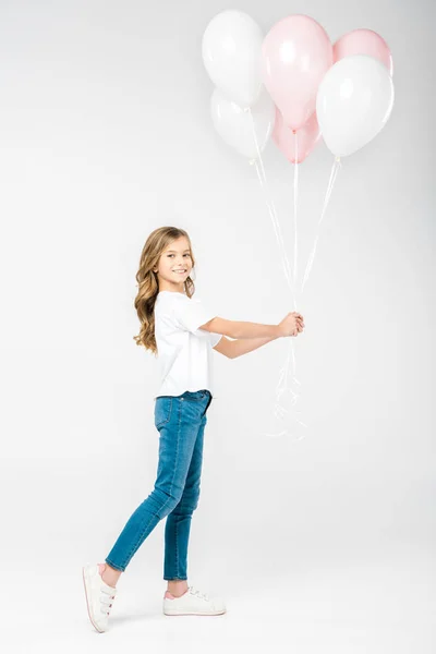 Cute smiling child holding festive white and pink air balloons on white background — Stock Photo