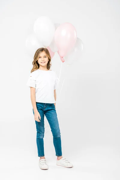 Criança bonito em t-shirt branca e jeans azul segurando balões de ar festivo no fundo branco — Fotografia de Stock