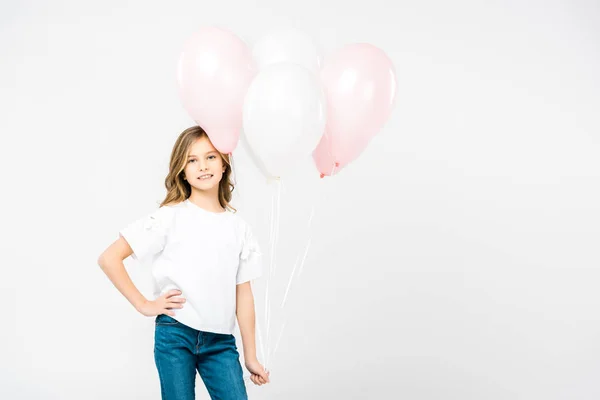 Enfant souriant avec la main sur la hanche tenant des ballons à air sur fond blanc — Photo de stock