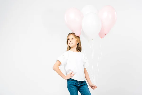 Cute child with hand in pocket holding festive air balloons on white background — Stock Photo