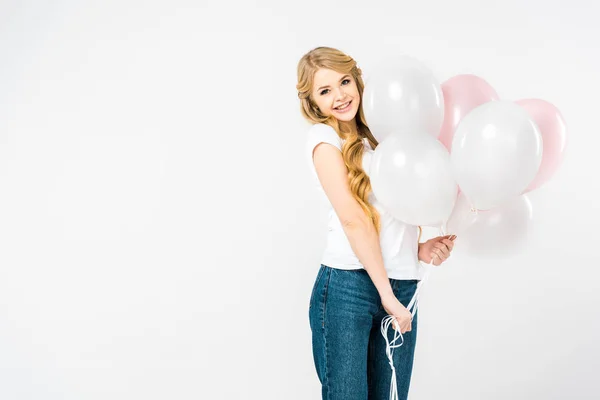 Hermosa mujer sonriente sosteniendo globos de aire y mirando a la cámara sobre fondo blanco - foto de stock