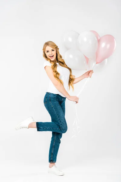 Happy beautiful woman holding festive air balloons while standing on one leg on white background — Stock Photo