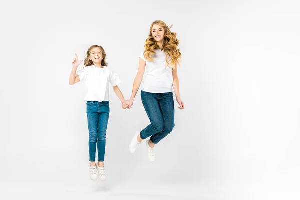 Glückliche Mutter mit entzückender Tochter springt auf weißem Hintergrund — Stockfoto