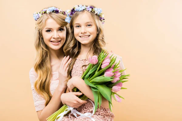 Schöne Mutter und glückliches Kind mit einem Strauß Tulpen, die lächeln und in die Kamera auf gelbem Hintergrund schauen — Stockfoto