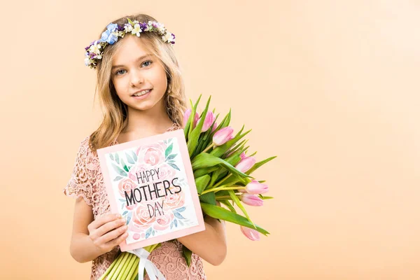 Adorable child with bouquet of pink tulips and happy mothers day greeting card on yellow background — Stock Photo