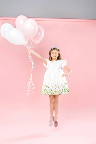 Criança despreocupada pulando com balões de ar branco e rosa no fundo bicolor — Fotografia de Stock