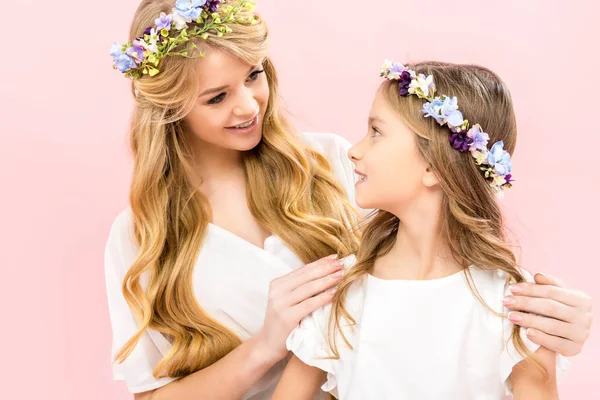 Bella madre che tiene adorabile figlia dalle spalle e teneramente guardando gli occhi su sfondo rosa — Foto stock