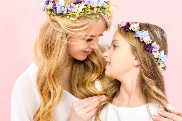 Beautiful mother hugging adorable daughter and looking at eyes on pink background — Stock Photo