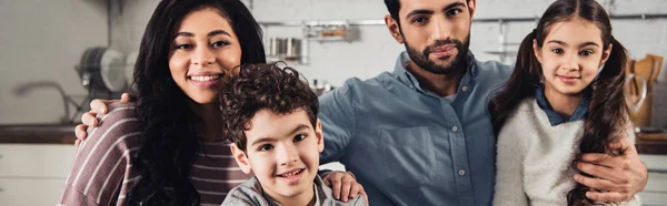 Alegre familia hispana sonriendo mientras mira la cámara en casa - foto de stock