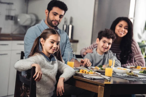 Foyer sélectif de heureux enfant hispanique souriant tout en regardant la caméra avec la famille latino sur fond — Photo de stock