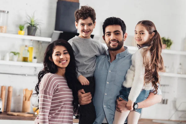 Bonito latina pai segurando em braços bonito filha e filho perto atraente esposa — Fotografia de Stock