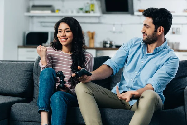 Cheerful latin woman celebrating victory while holding joystick near husband after playing video game — Stock Photo