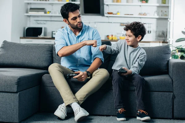 Felice padre latino dando pugno al figlio dopo aver giocato al videogioco a casa — Foto stock