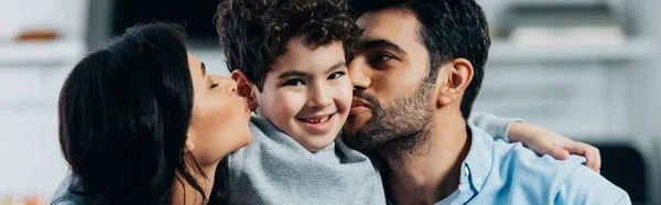 Feliz pai latino e mãe beijando bochechas de filho adorável em casa — Fotografia de Stock