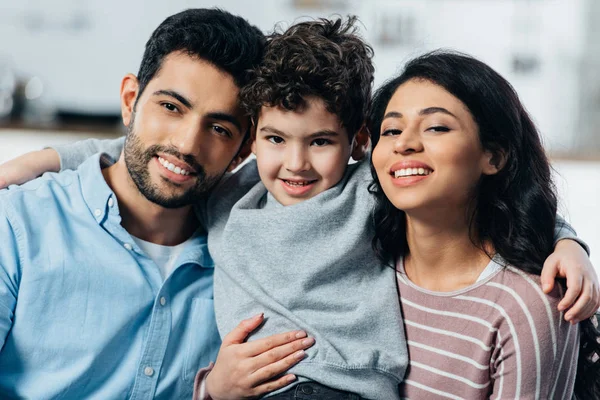 Glückliche lateinische Familie umarmt, während sie zu Hause in die Kamera schaut — Stockfoto